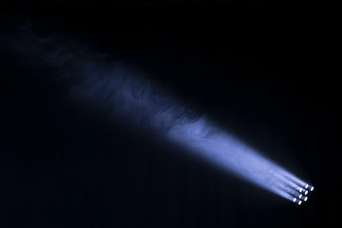 A spotlight shining in the dark through a cloud of mist, casting a volumetric light in the mist